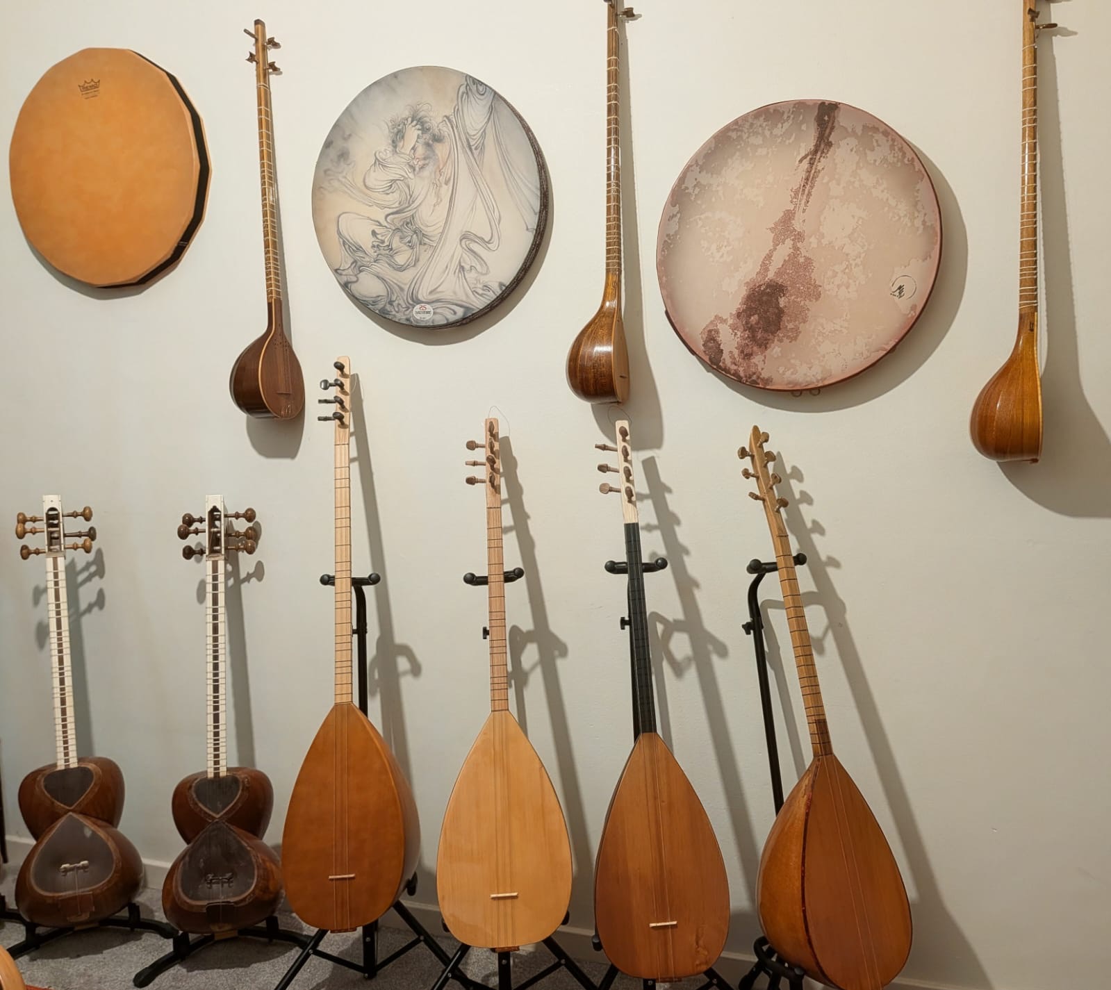 A wall of instruments: frame drums, setars, tars and bağlamas on stands